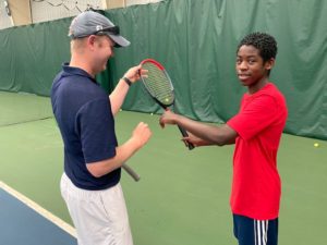 Instructor giving teen tennis lessons